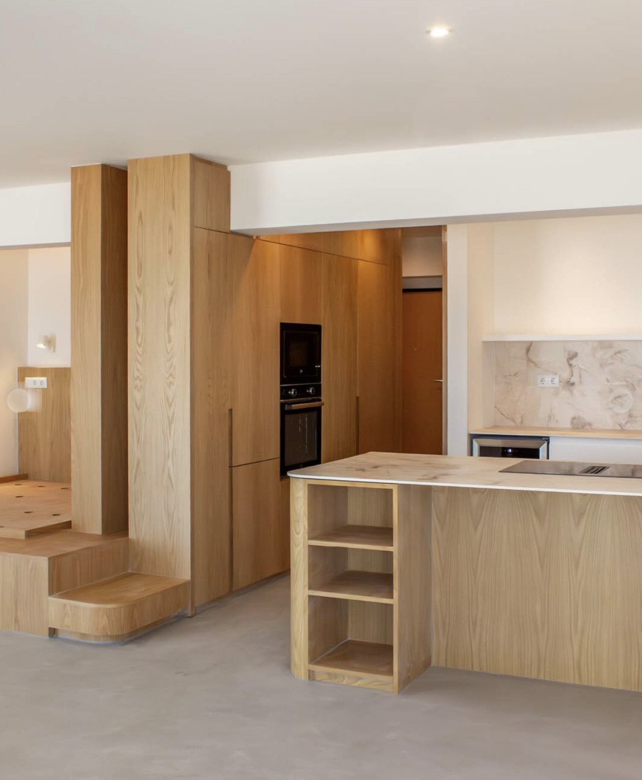 Warm wood-toned modern interior with staircase and kitchen island